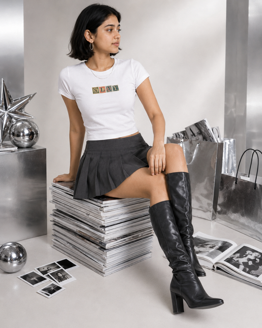 Woman in a white t-shirt and black skirt sitting on a stack of books in a metallic interior.