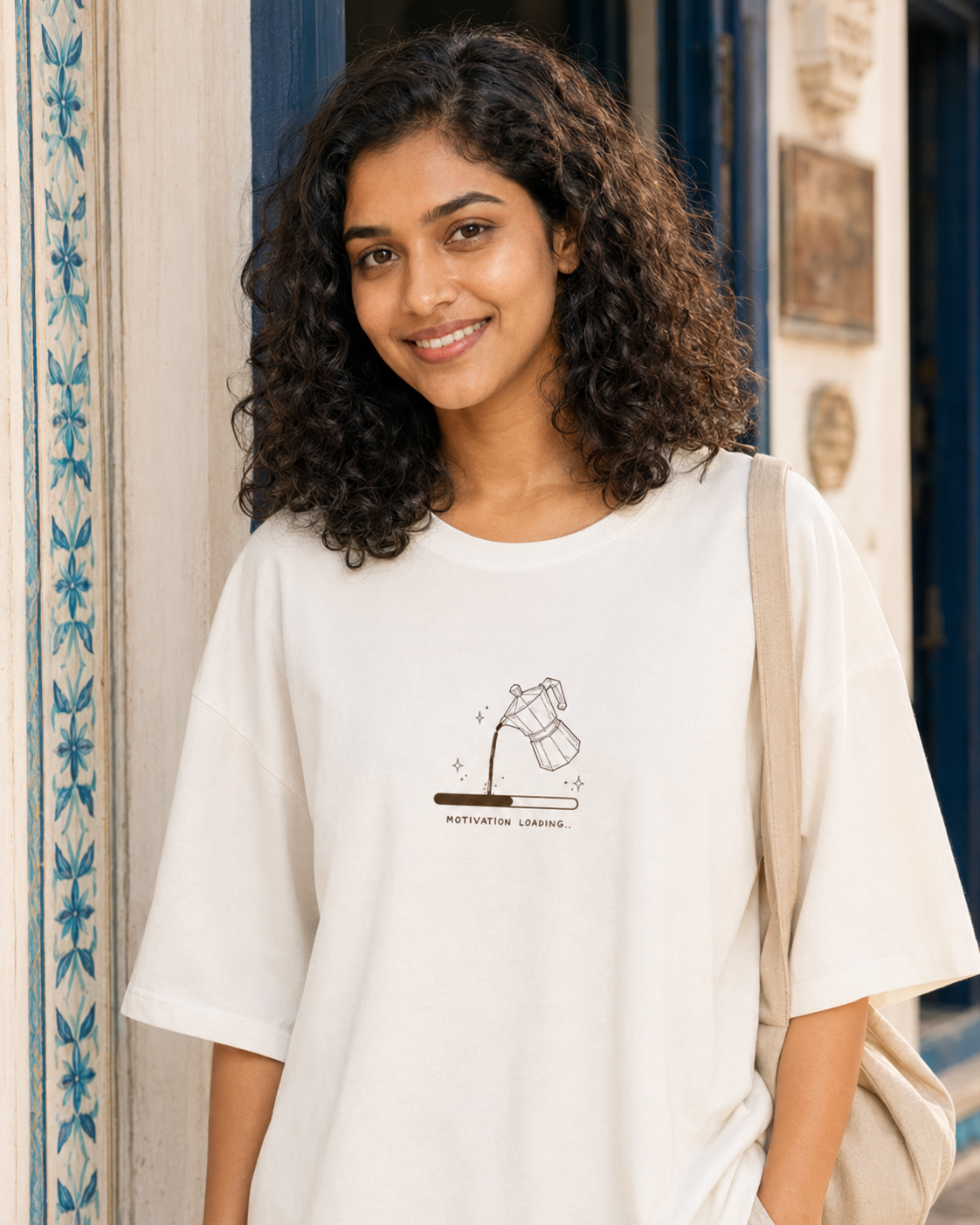 Woman wearing a white t-shirt with a graphic design, standing in front of a building entrance.