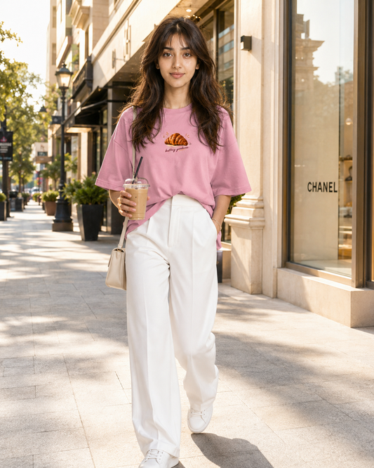 Girl wearing Croissantholic oversized graphic t shirt in pink color on city street