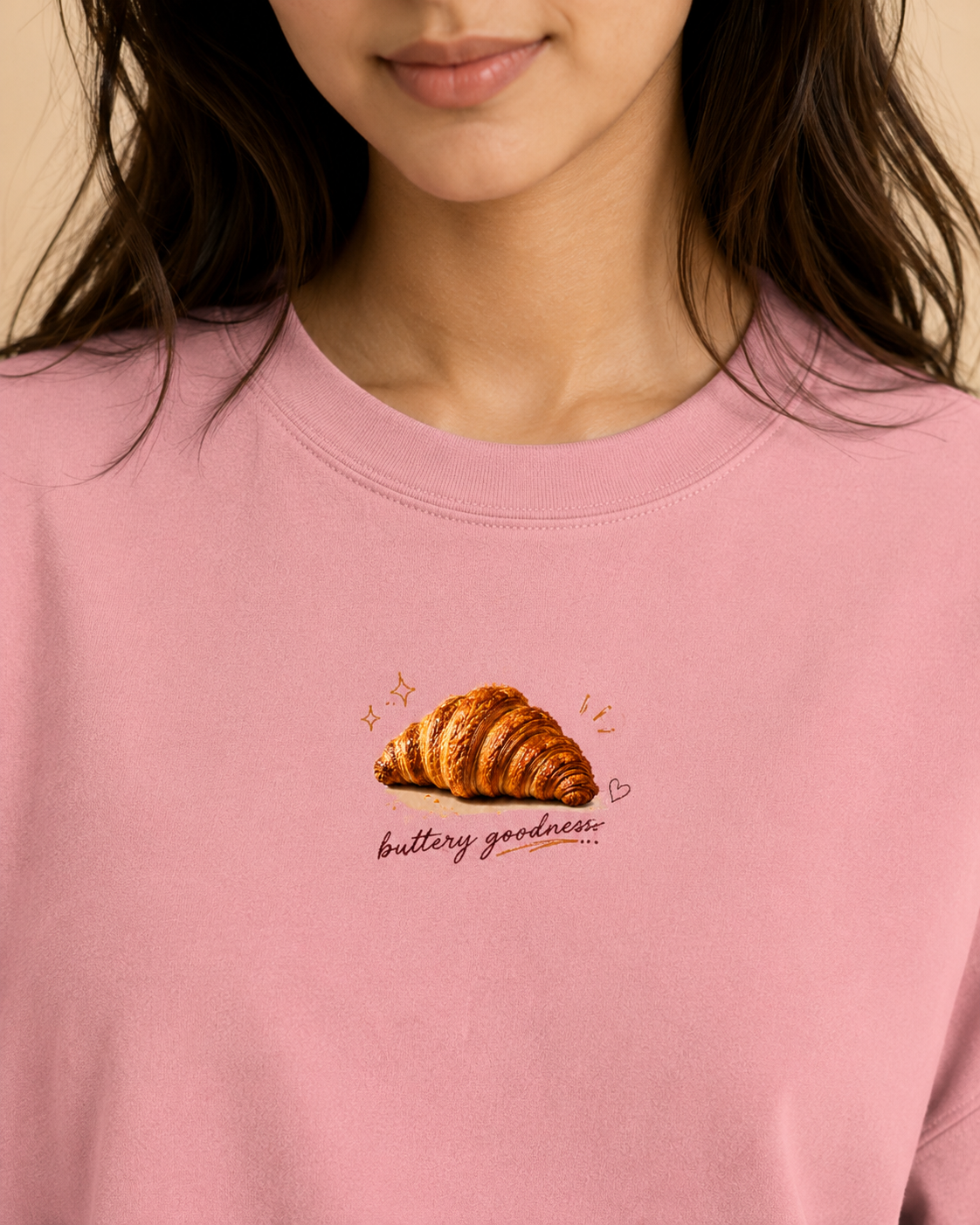 Pink sweatshirt with a croissant graphic and text on a beige background