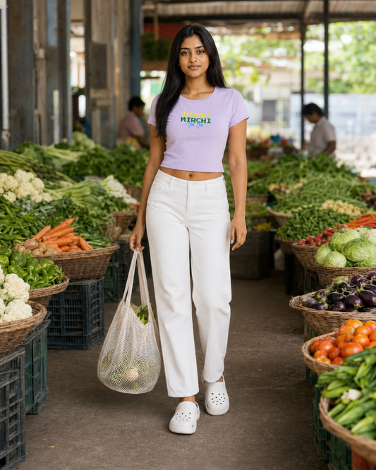 Woman holding a reusable bag in an outdoor market with vegetables around her.