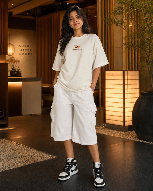 Woman wearing a white t-shirt with a logo and white shorts in an indoor setting.