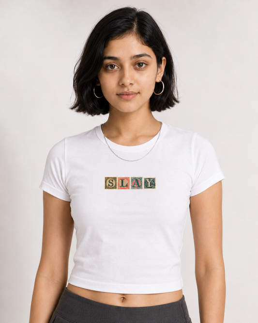 Person wearing a white t-shirt with 'SLAY' text design on a plain background